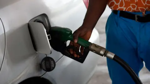 Getty Images Man fills car petrol tank in Nigeria