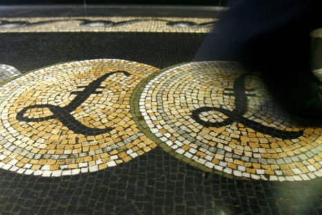 File photograph shows an employee walking over a mosaic depicting pound sterling symbols on the floor of the front hall of the Bank of England in London