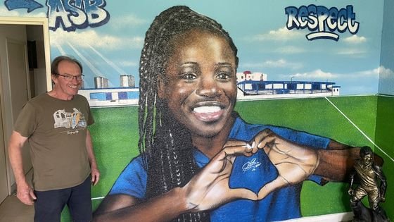Michel Le Lann pose fièrement à côté de la fresque représentant Griedge Mbock
