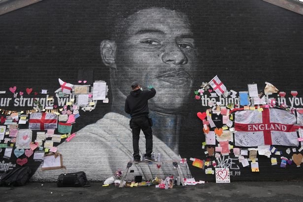 The artist known as AKSE_P19, who painted the mural of England footballer Marcus Rashford which is displayed on the wall of a cafe on Copson Street, Withington, sets about repairing it after it was defaced by vandals in the aftermath of England's Euros loss on July 13, 2021 in Manchester, England. 