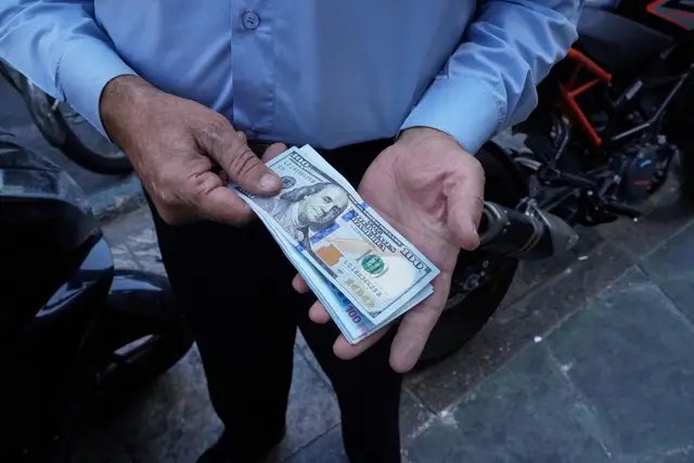 A street money exchanger holding US and Iranian banknotes