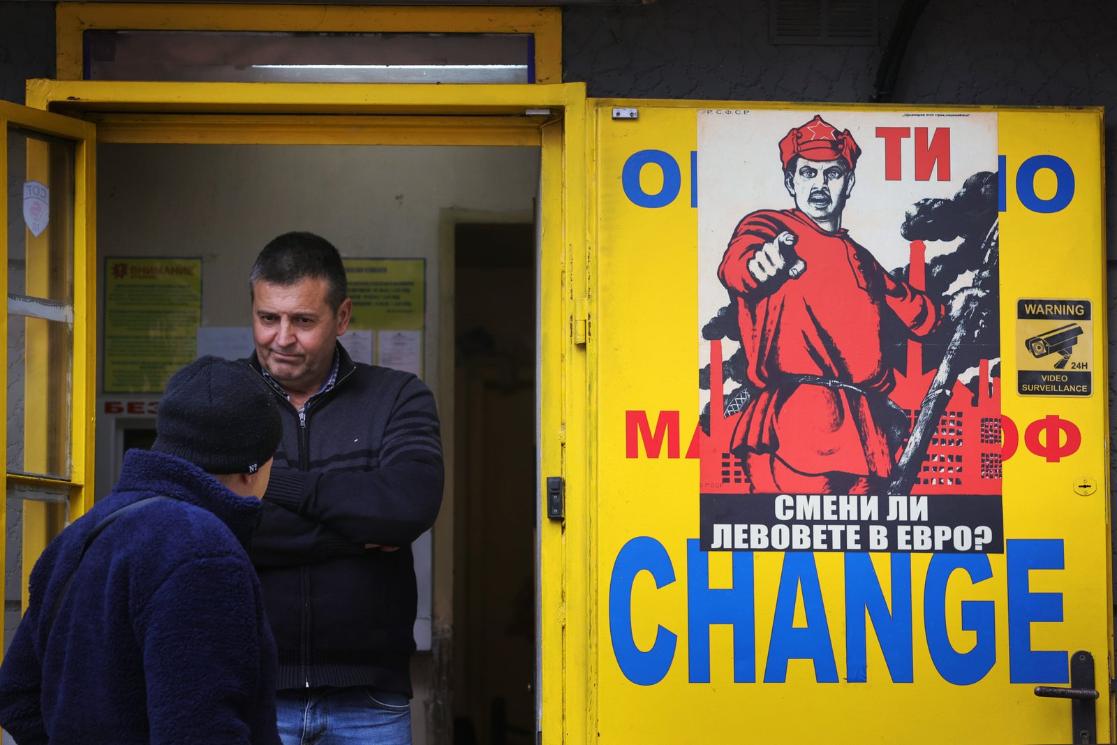 People stand at a currency exchange office with a poster reading 